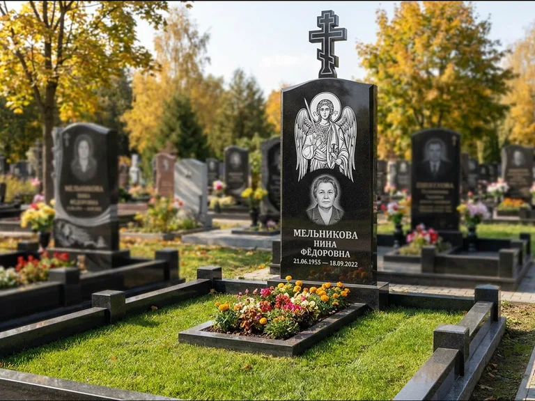 Памятник с гравировкой иконы: округлая стела-медальон с ликом — гравировка Богородицы «Семистрельная», луговые травы и полевые цветы за участком, работа «Гущин» в Кемерово