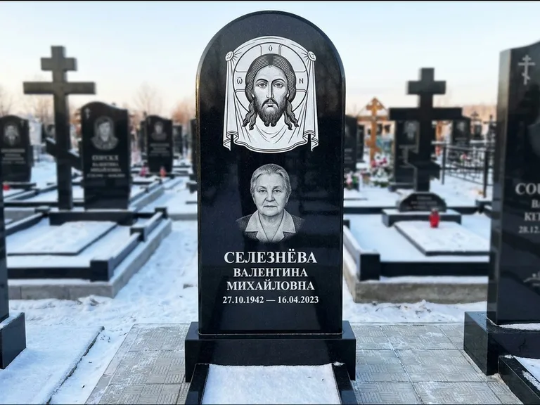 Памятник с гравировкой иконы: небольшая скромная одиночная стела с именной иконой — золочёный нимб на образе, аккуратный участок с газоном, работа «Ковалёв» в Кемерово