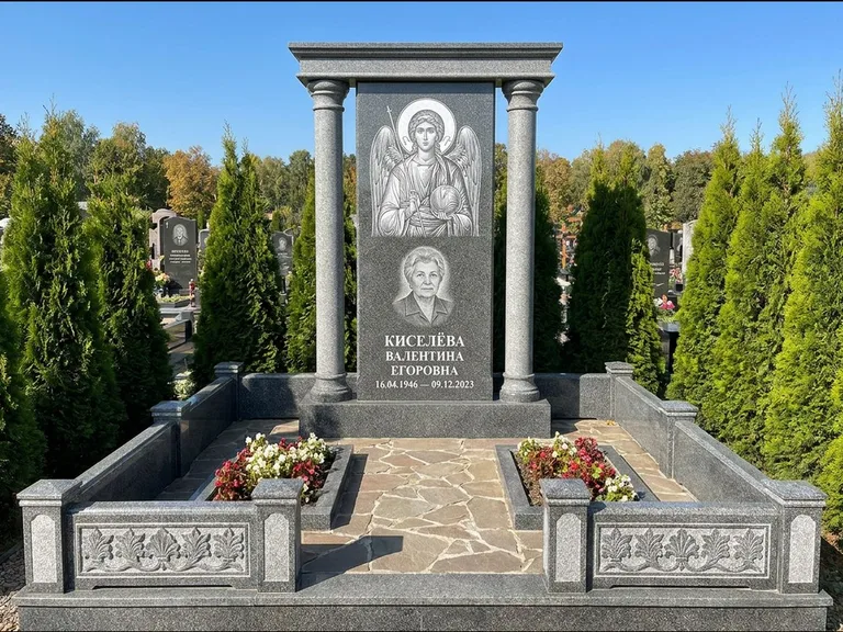 Памятник с гравировкой иконы: массивная стела с двускатным навершием-домиком — гравировка Николая Чудотворца, живая изгородь из туи, работа «Журавлёв» в Кемерово