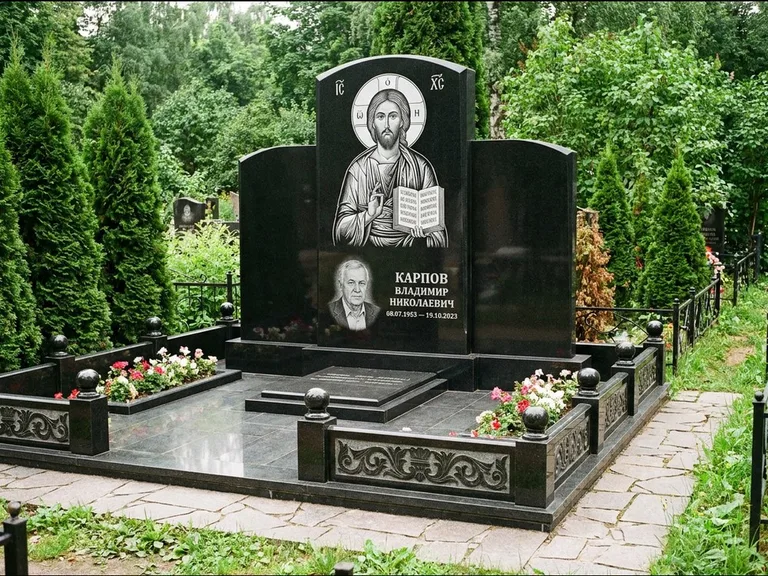 Памятник с гравировкой иконы: широкая панорамная стела с золочёным нимбом — гравировка образа Матроны Московской, цветник с белыми хризантемами, работа «Мельникова» в Кемерово