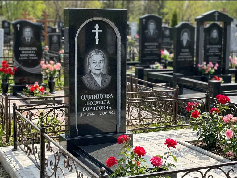 Памятник из чёрного гранита — скромная невысокая стела с крестом с терновым венцом, работа «Лаврентьева» в Кемерово