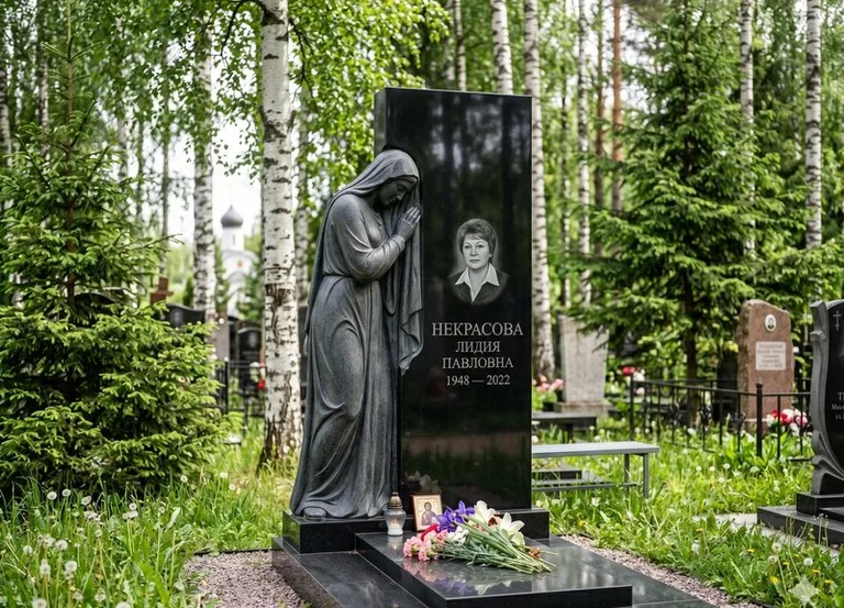 Гранитная фигура скорбящего мужчины у чёрной стелы в Кемерово